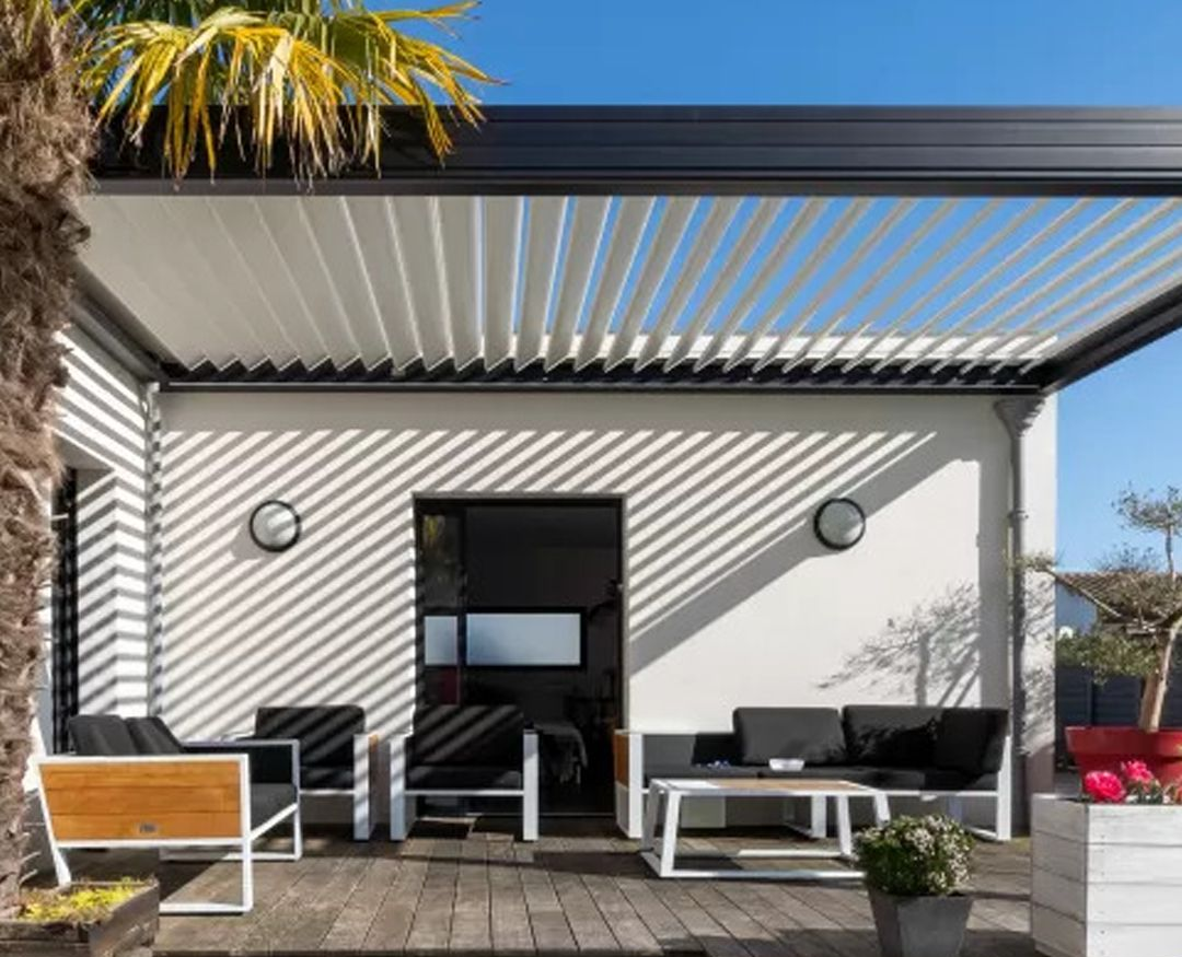 Patio moderno con pergola a righe, posti a sedere all'aperto, panchina in legno e una piccola pianta in vaso in pieno sole.