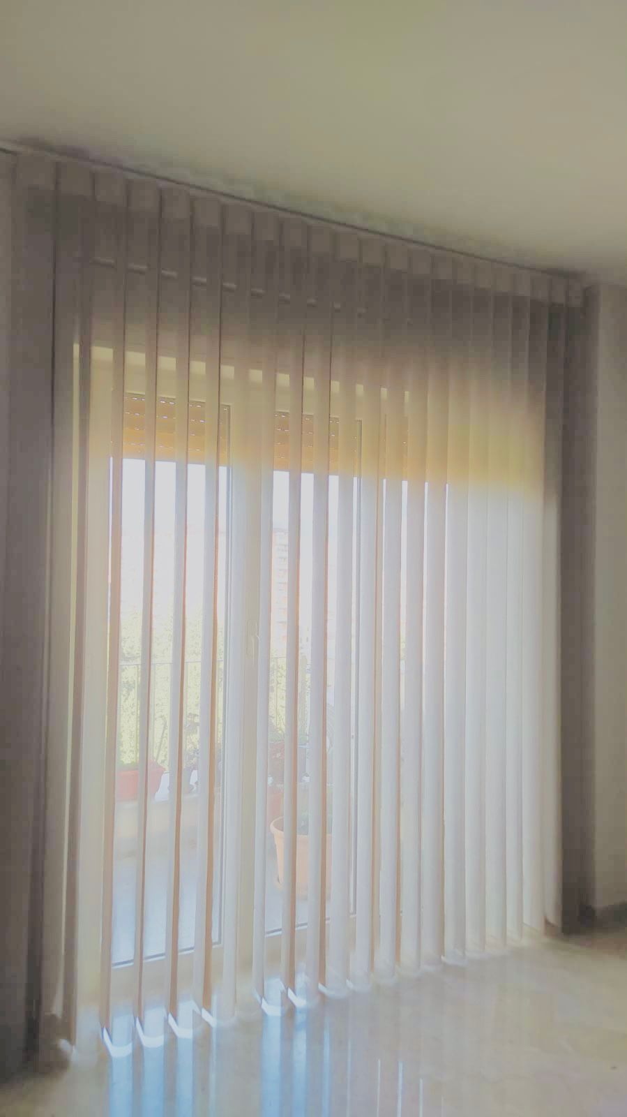 Tende trasparenti a tutta altezza con drappeggi grigi su una finestra luminosa o una porta scorrevole.