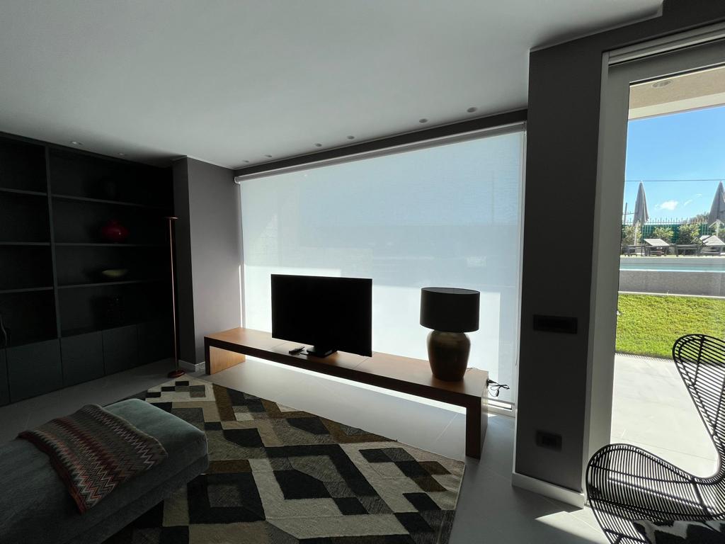 Camera da letto moderna con ampia finestra, mobili neri e vista sul verde esterno.