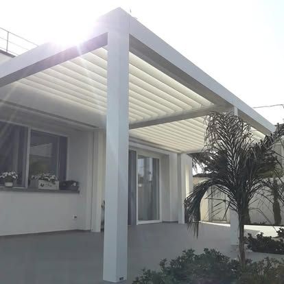 Patio moderno bianco con tettoia a pergola e porte scorrevoli in vetro, visto dal giardino anteriore.