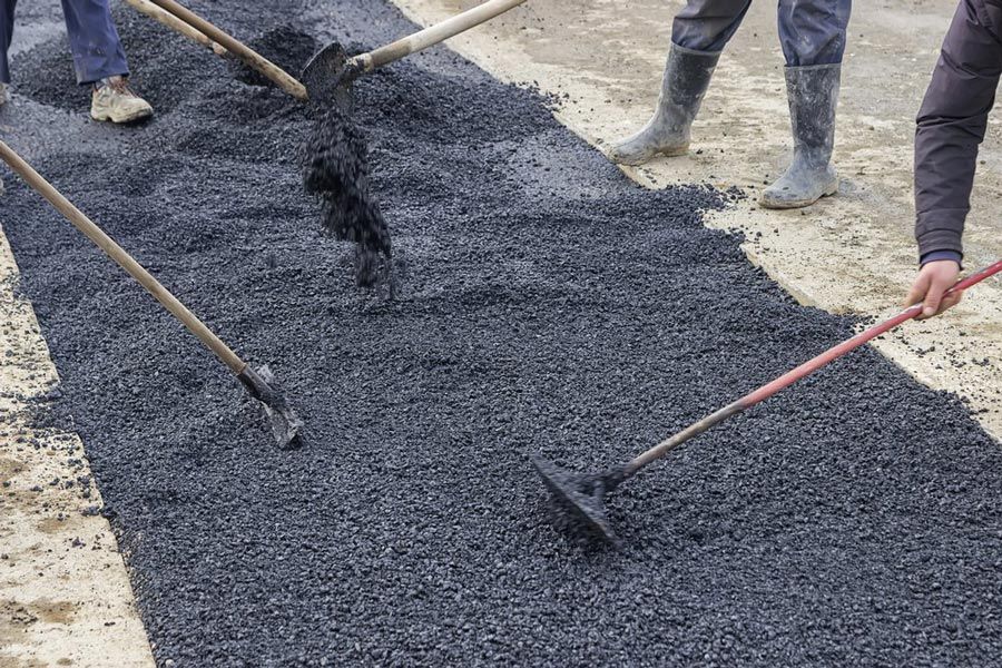 Road Construction Crew Scattering Asphalt Evenly — Bitumen Services in Darwin, NT