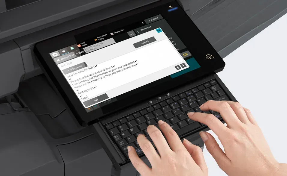 Person typing on a keyboard connected to a multifunction printer's touchscreen interface.