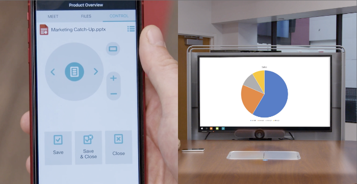 A person uses a smartphone to control a pie chart displayed on a computer monitor. The chart is on a desk.