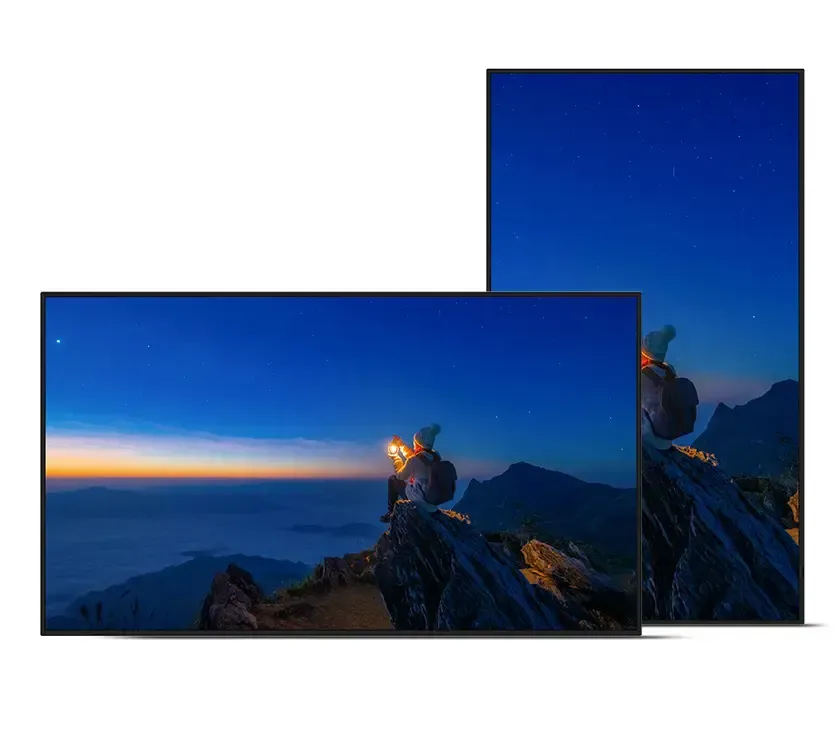 Two monitors display a night mountain scene: a person on a peak, stars, dark blue sky, and a colorful sunrise.