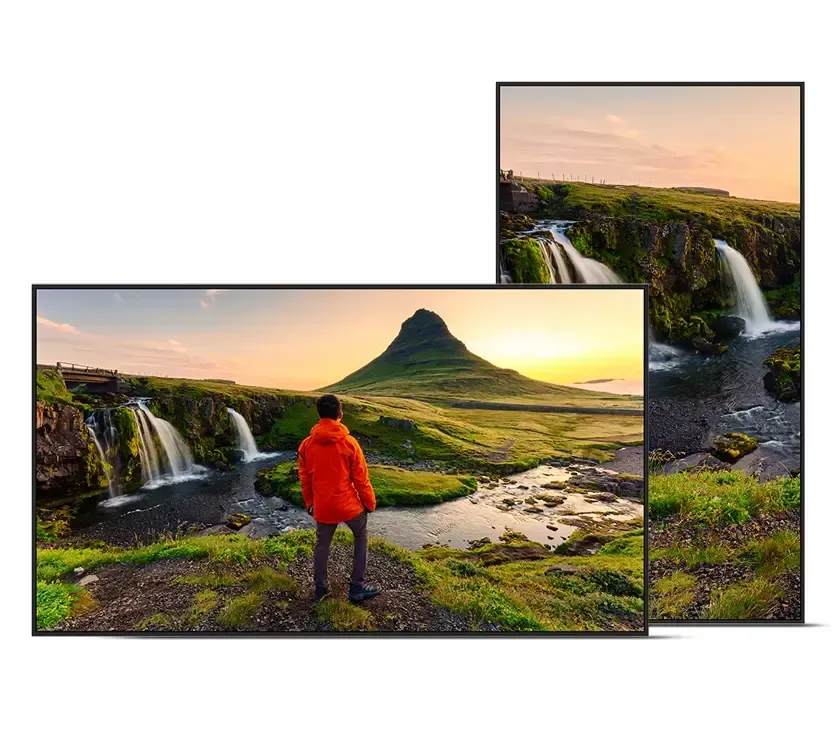 Person in orange jacket standing before waterfall; screens displaying scenic landscape, one vertical.
