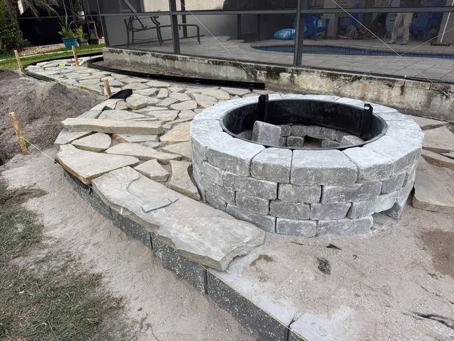 Stone fire pit beside a flagstone patio and steps in an outdoor yard