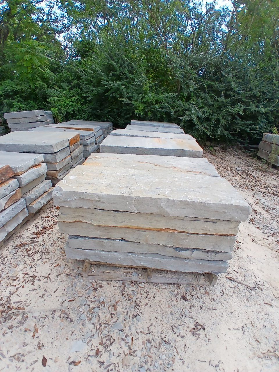 Stacked stone slabs in an outdoor yard with trees in the background