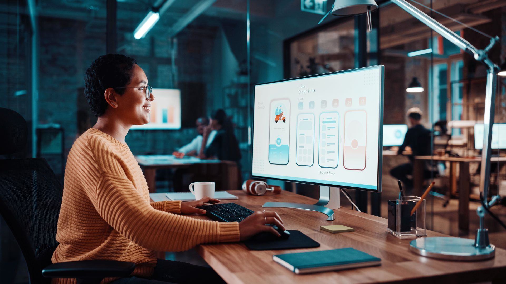 Uma profissionais de design UX analisando elementos gráficos em um layout no seu computador.