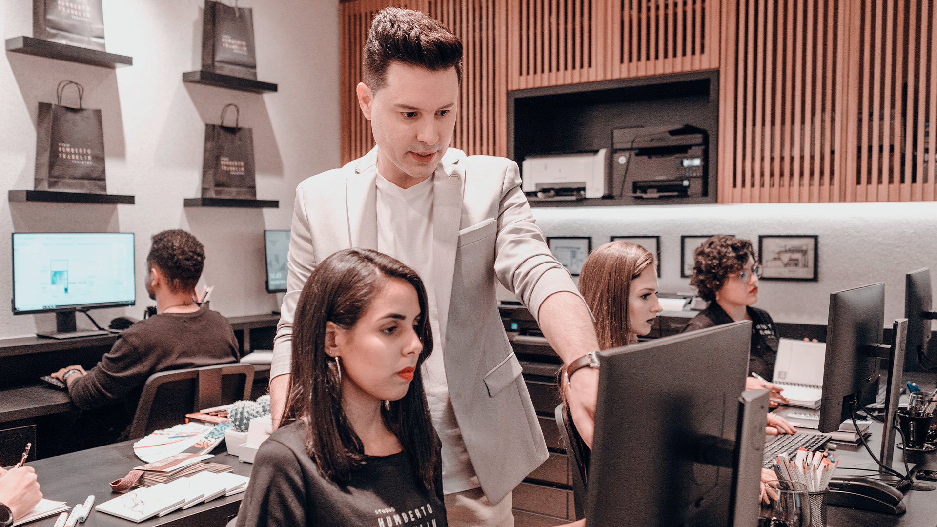Um homem ensinando uma mulher a usar um computador em um escritório.