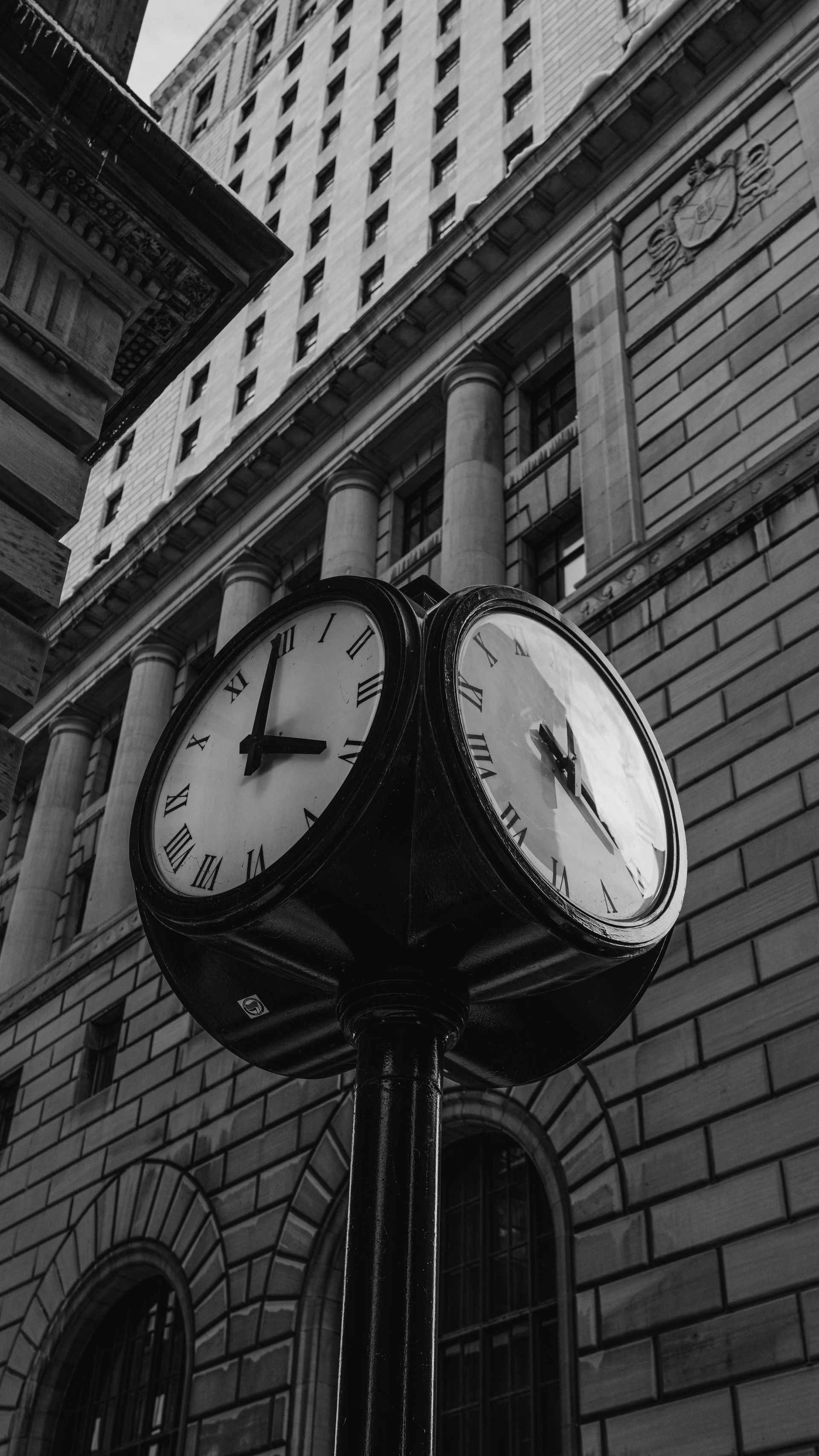 Street clock with three faces; building in background.