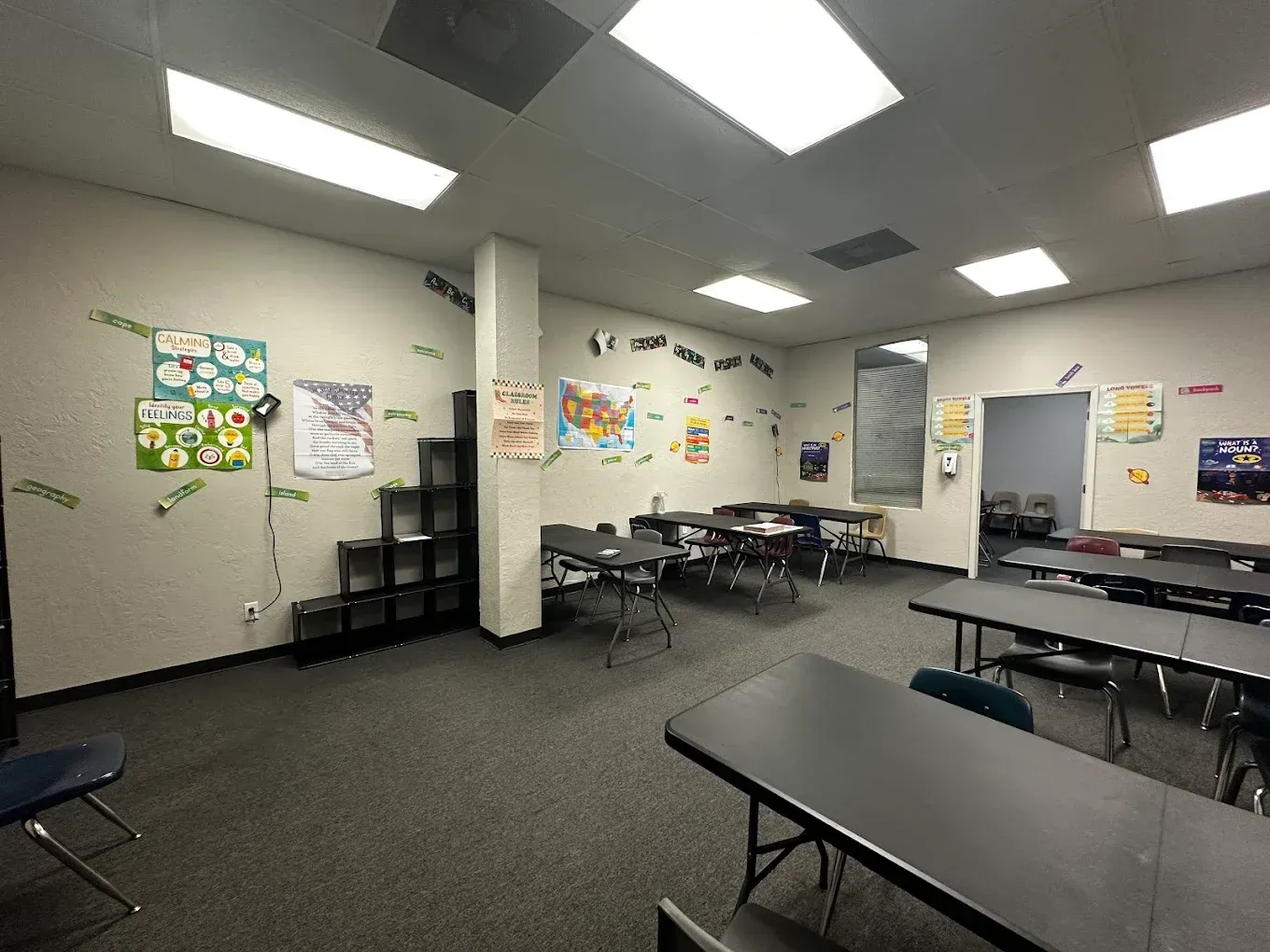 A classroom with tables and chairs and posters on the wall.
