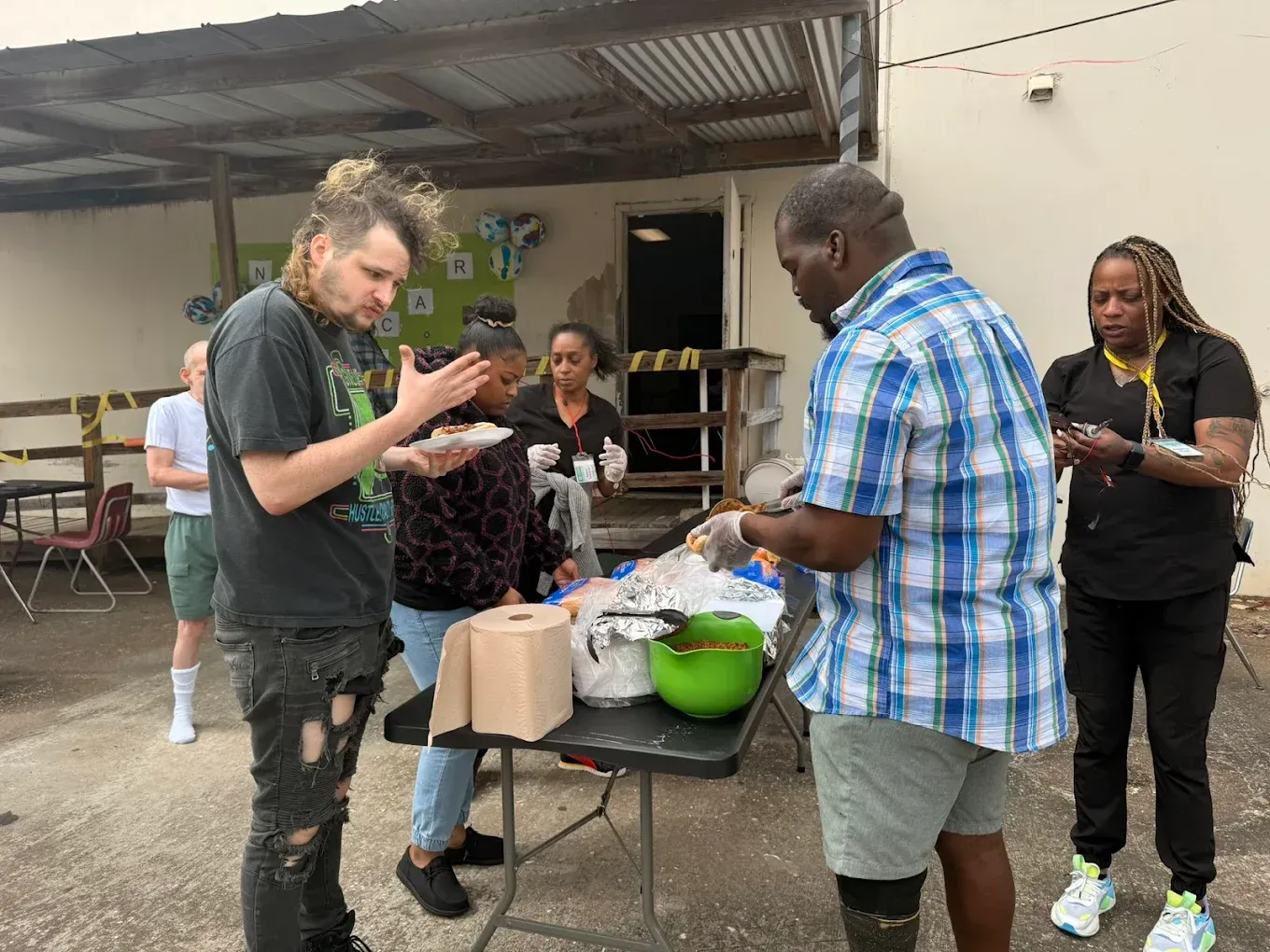 A group of people are standing around a table eating food.