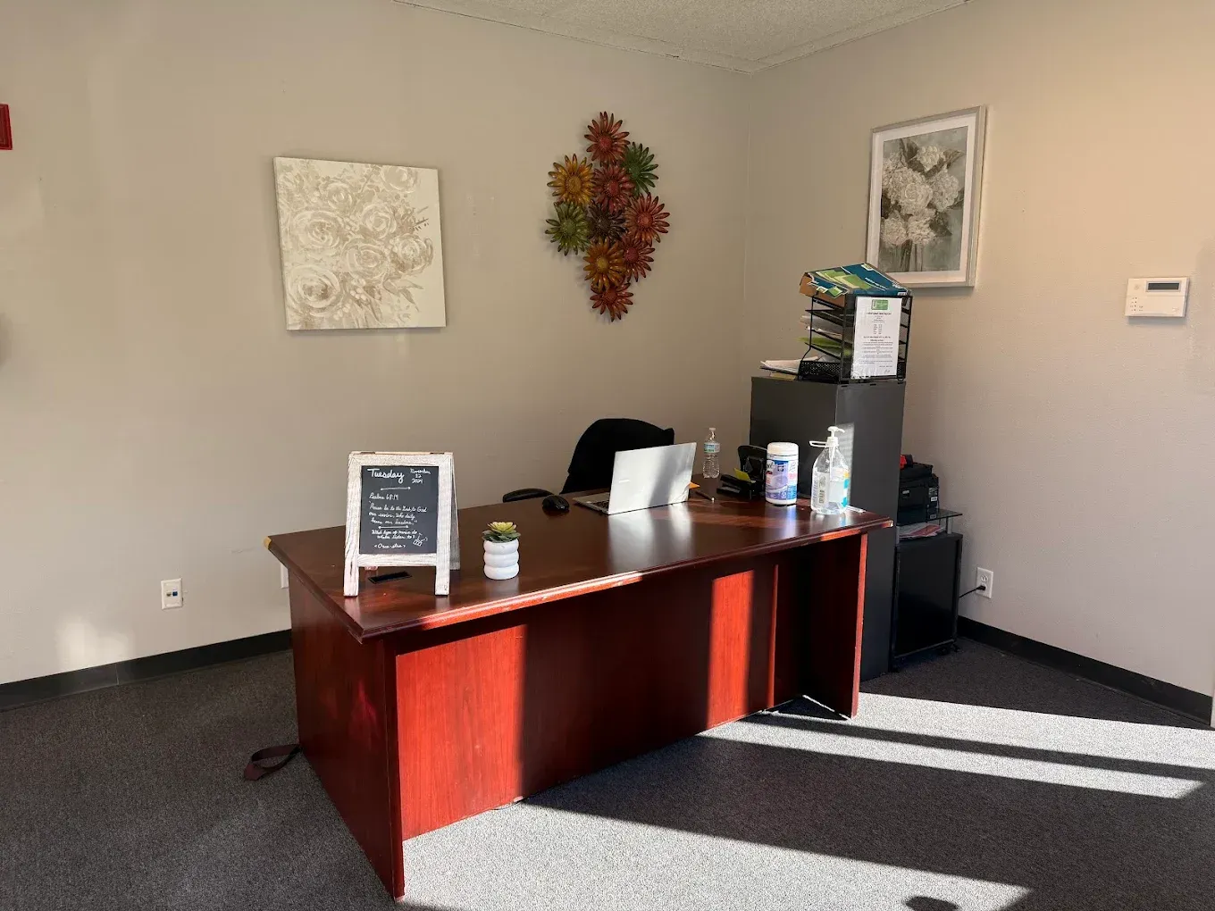 An office with a wooden desk and a chalkboard on the wall.