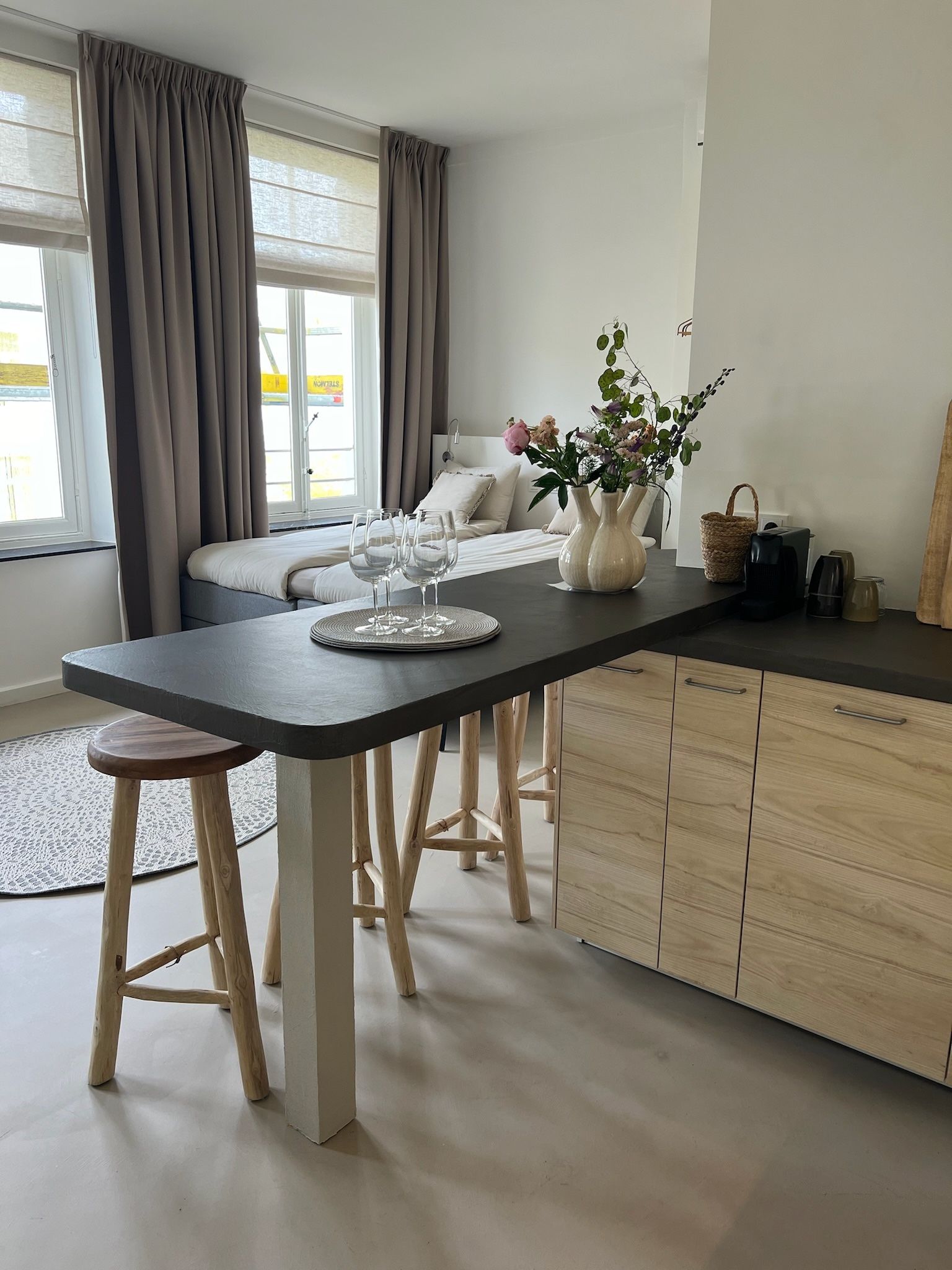 Gezellig studioappartement met een ontbijtbar, bed en raam met gordijnen.