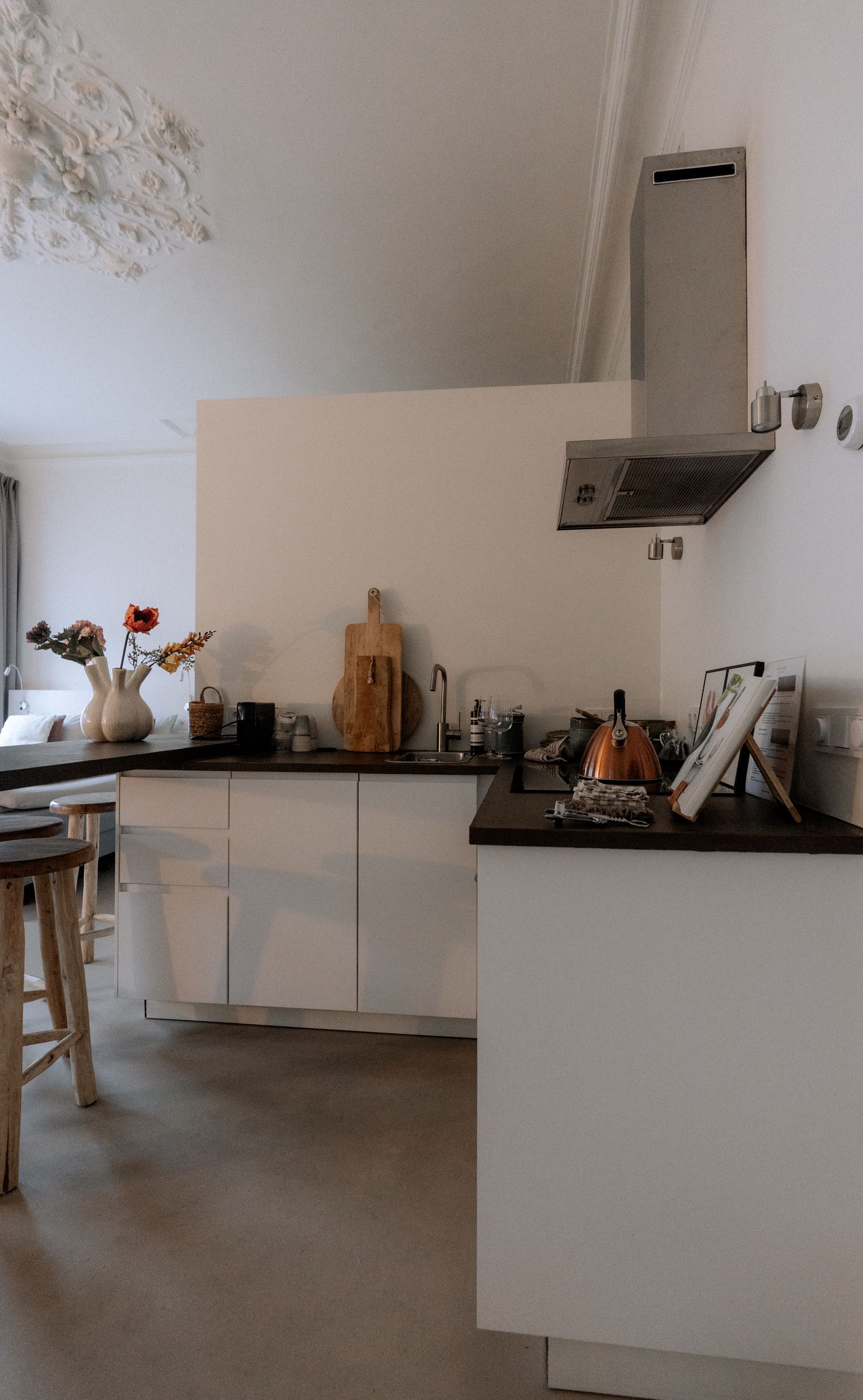Keuken met witte kasten, donker aanrechtblad en roestvrijstalen afzuigkap.