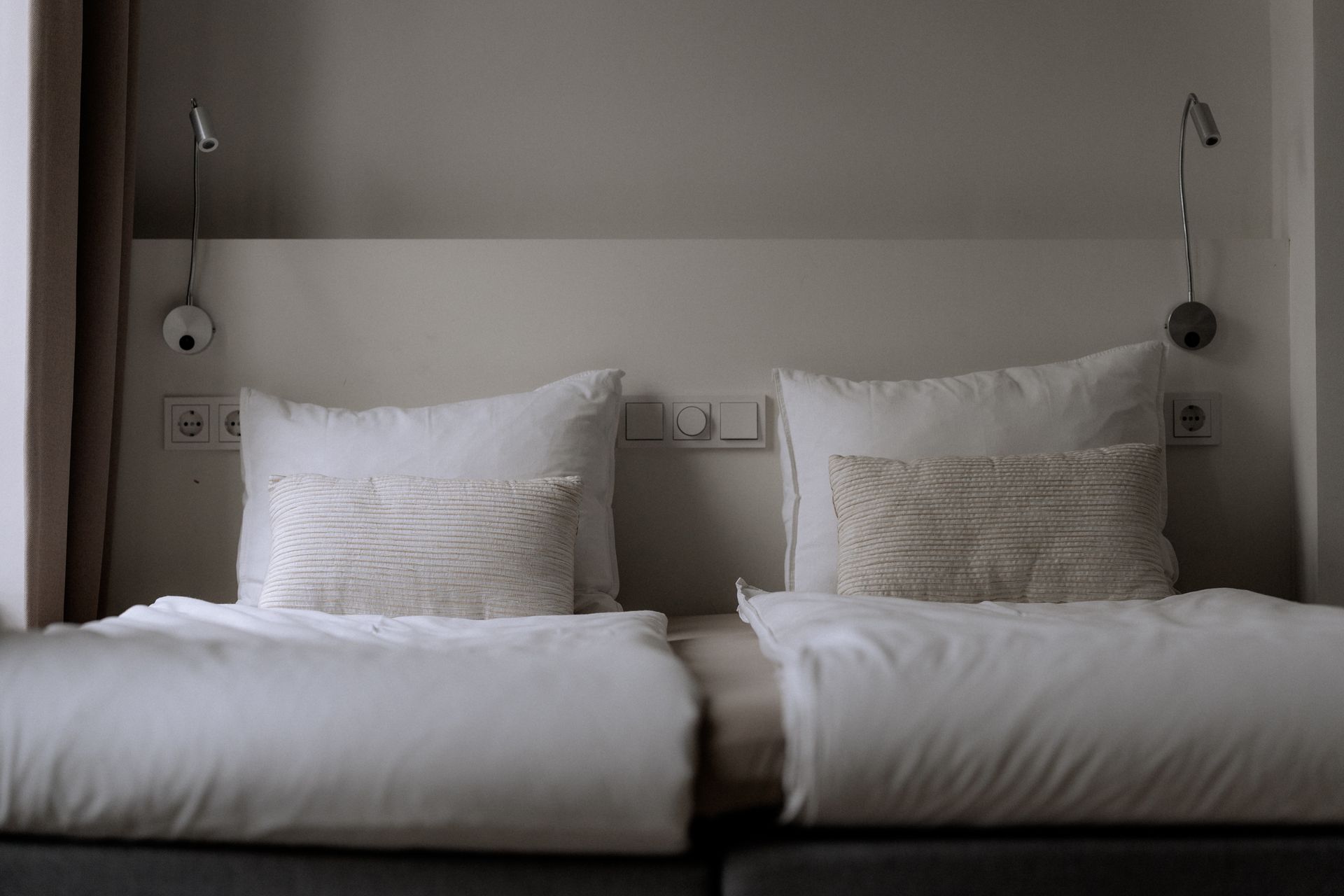 Twee bedden met witte lakens, witte kussens en bijpassende wanddecoratie.