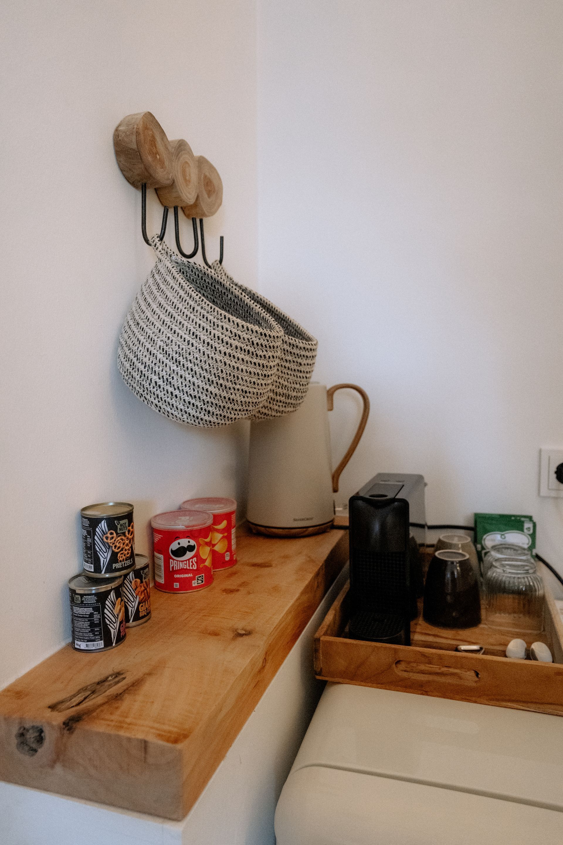 Houten plank in de hoek met snacks, een waterkoker, mokken en een hangmand.