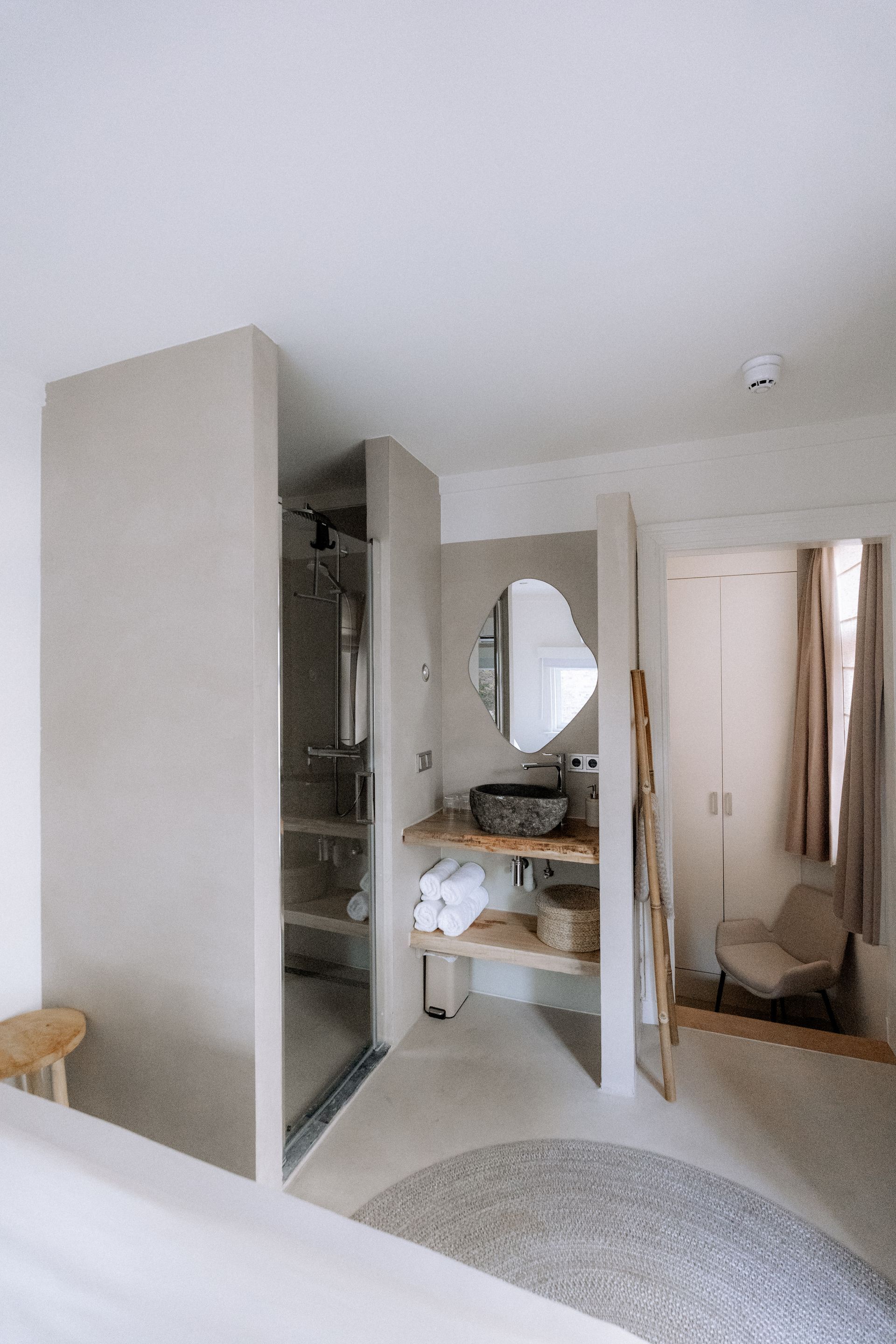 Badkamer met inloopdouche, wastafel en houten planken; neutrale kleuren en minimalistisch design.