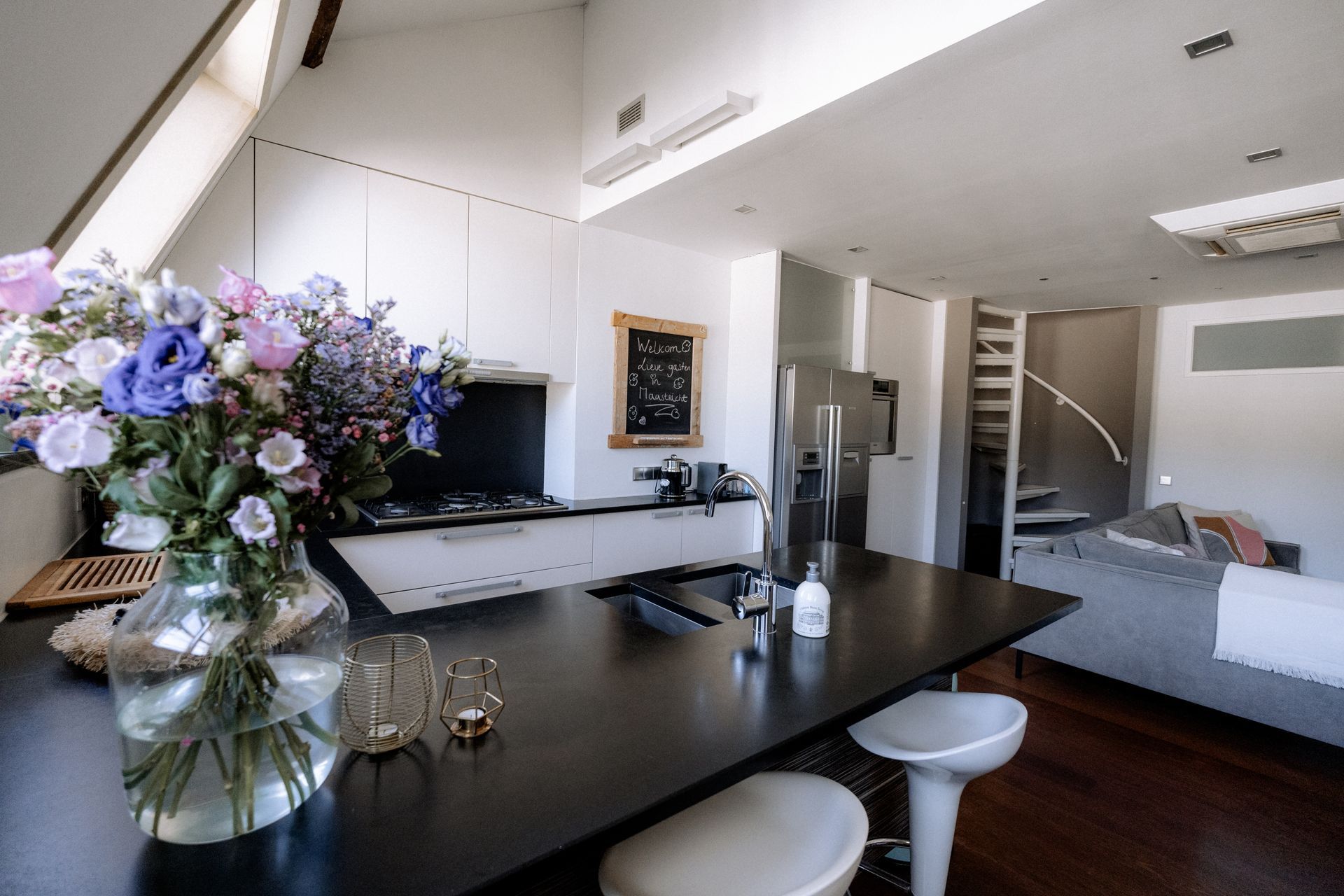 Moderne keuken met donker kookeiland, bloemen en witte kasten.