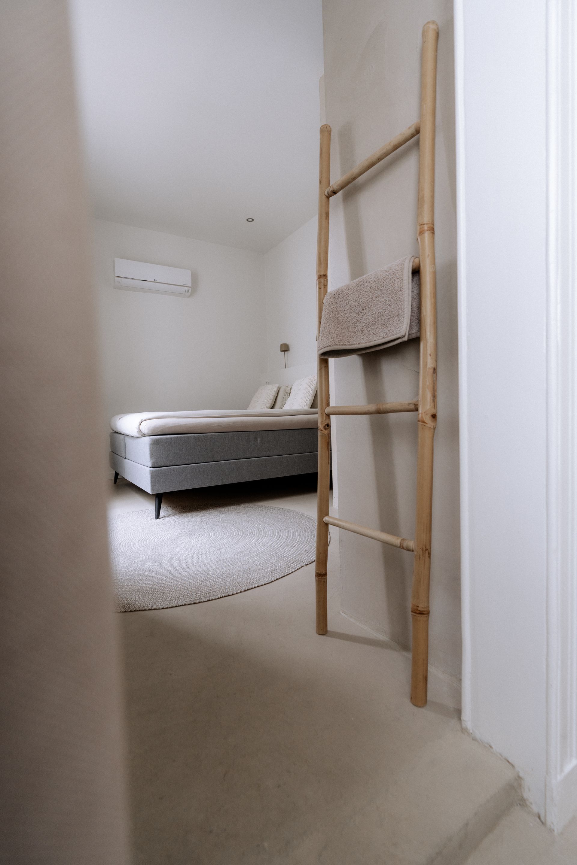 Slaapkamerinterieur met bed, vloerkleed en houten ladder met handdoek.