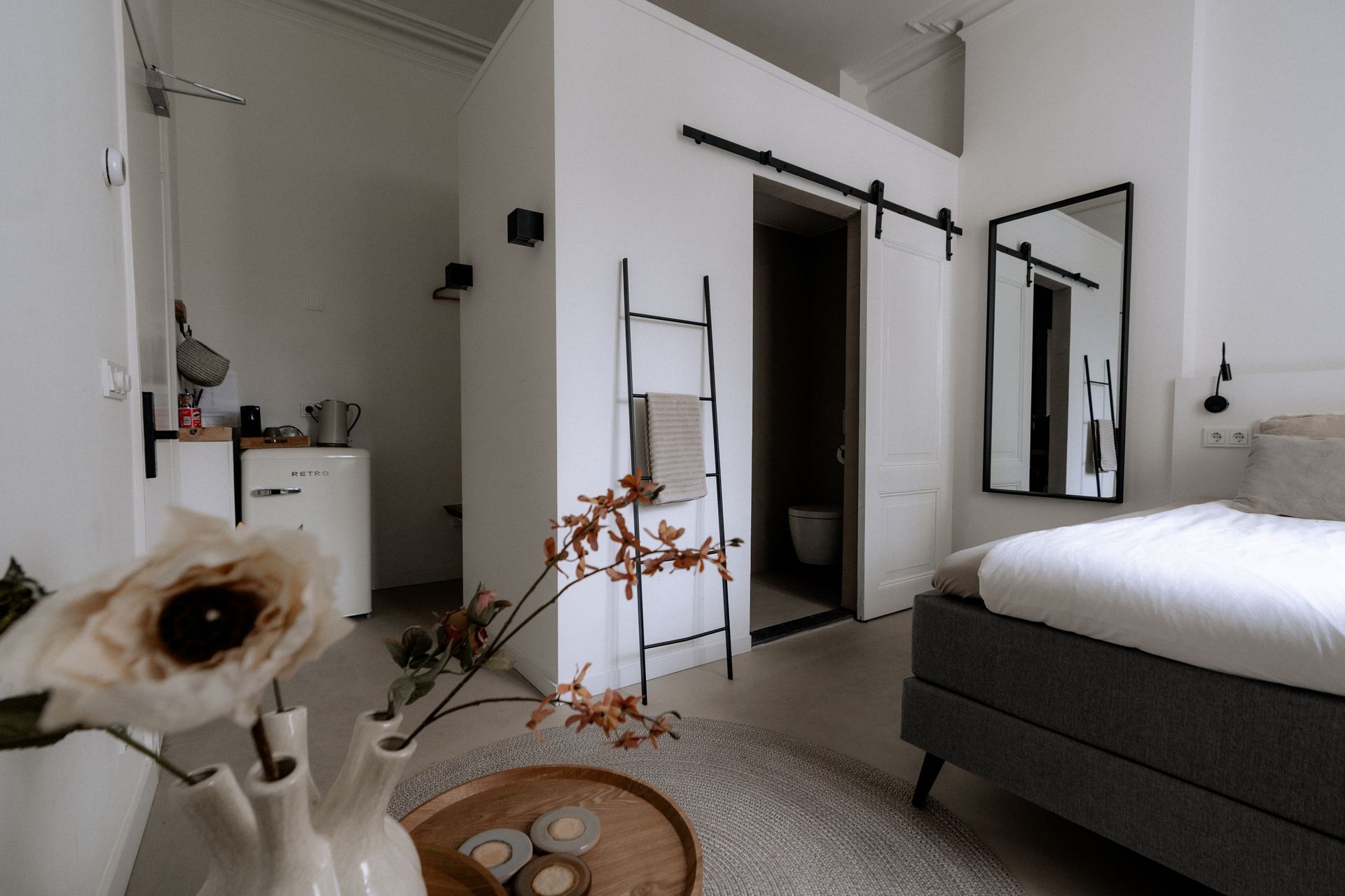 Modern wit studioappartement met slaapkamer, badkamer en keukenhoek.
