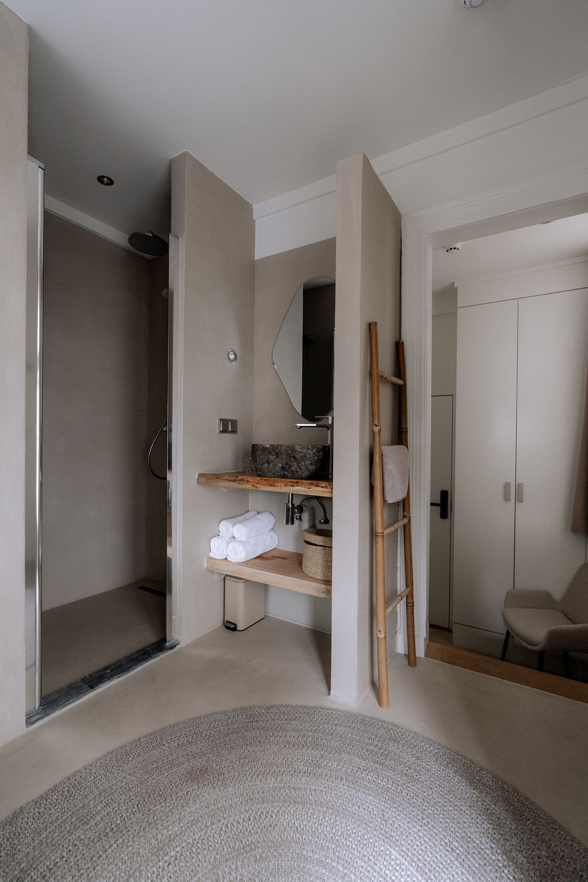 Moderne badkamer met beige muren, een douche, wastafel en een houten handdoekrek.