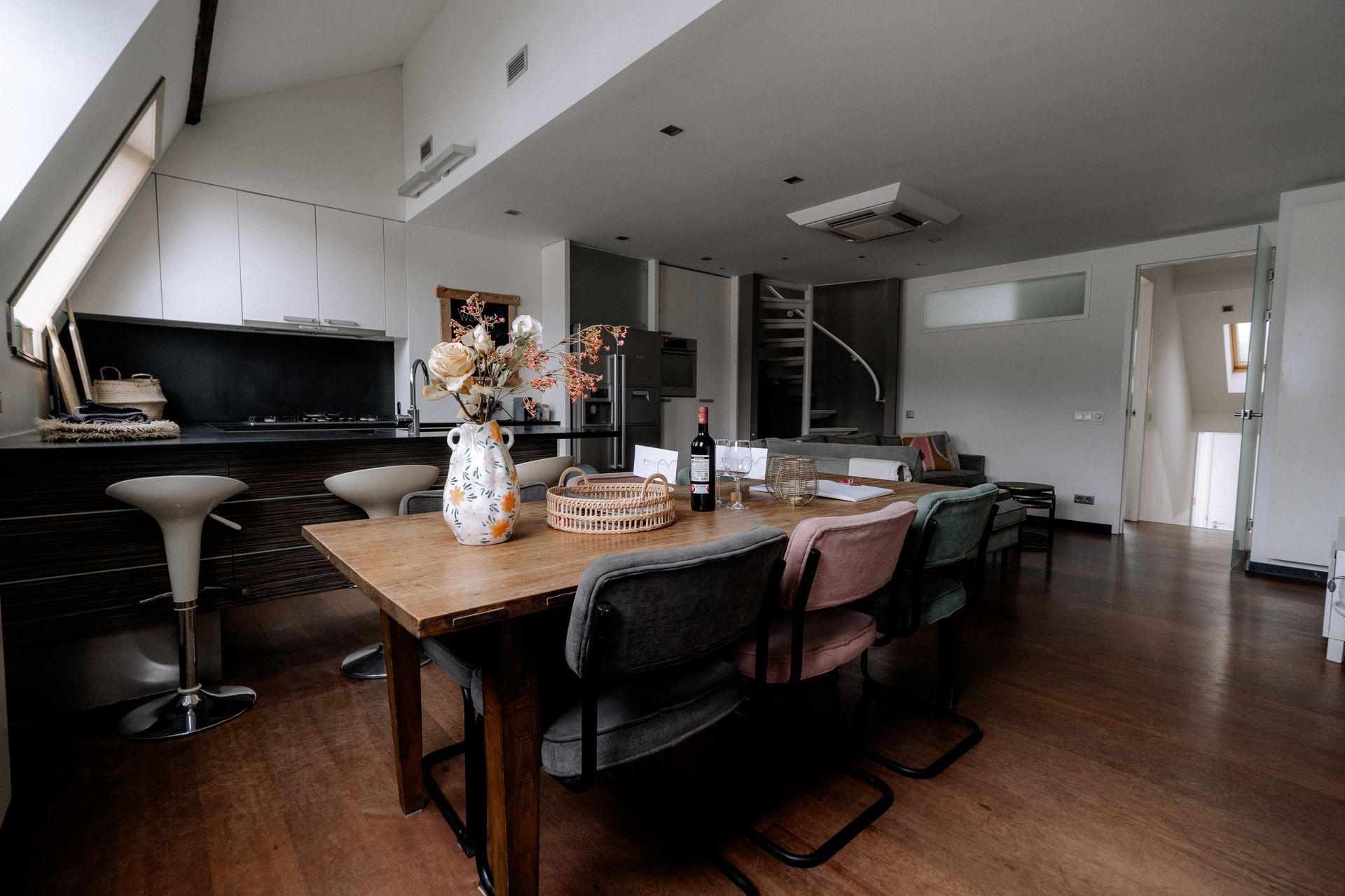 Open eetruimte met tafel, stoelen, keuken en trap in een moderne loft.