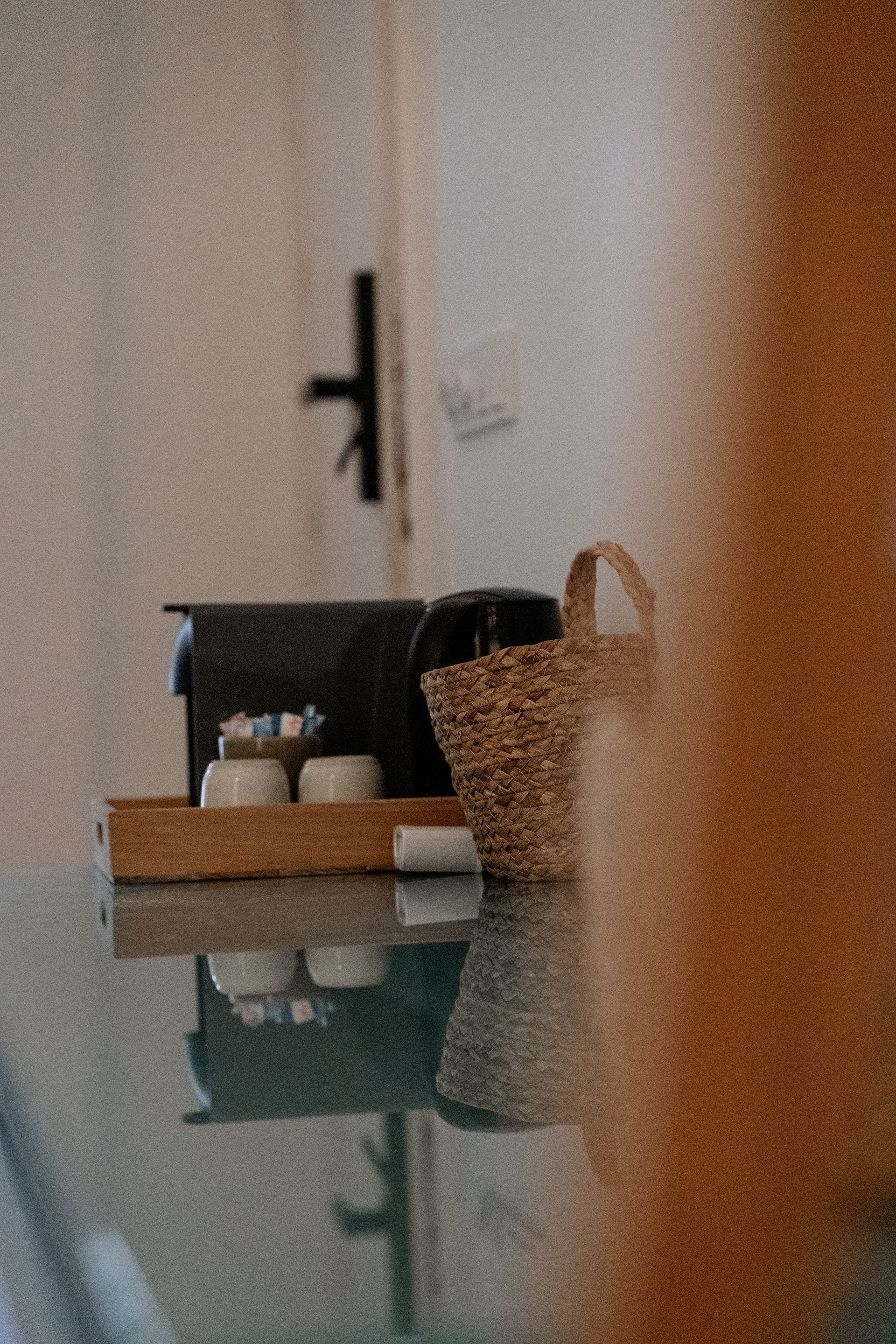 Een tafel met een mand, bakjes en een weerspiegeling. De scène is zacht verlicht, met neutrale tinten.