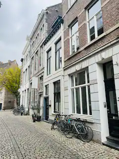 Een straat met kinderkopjes en gebouwen; fietsen staan langs de kant geparkeerd.