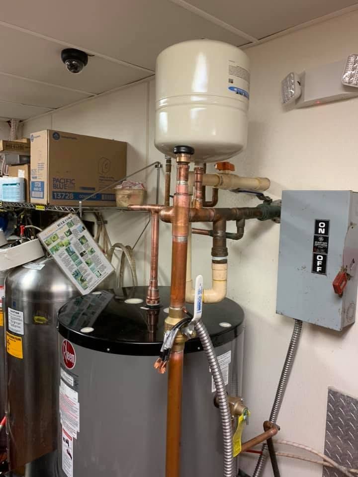 Utility room with water heater, plumbing pipes, control panel, and fire extinguisher