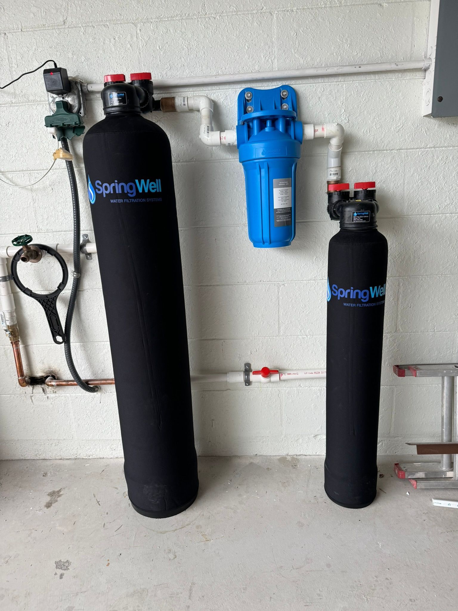 Gloved hands adjusting valves on a complex industrial pipe manifold with gauges and colored fittings