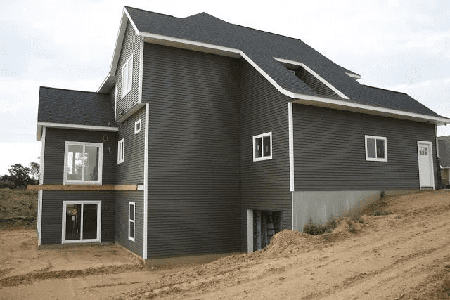 Modern dark-gray house under construction on a sandy hillside
