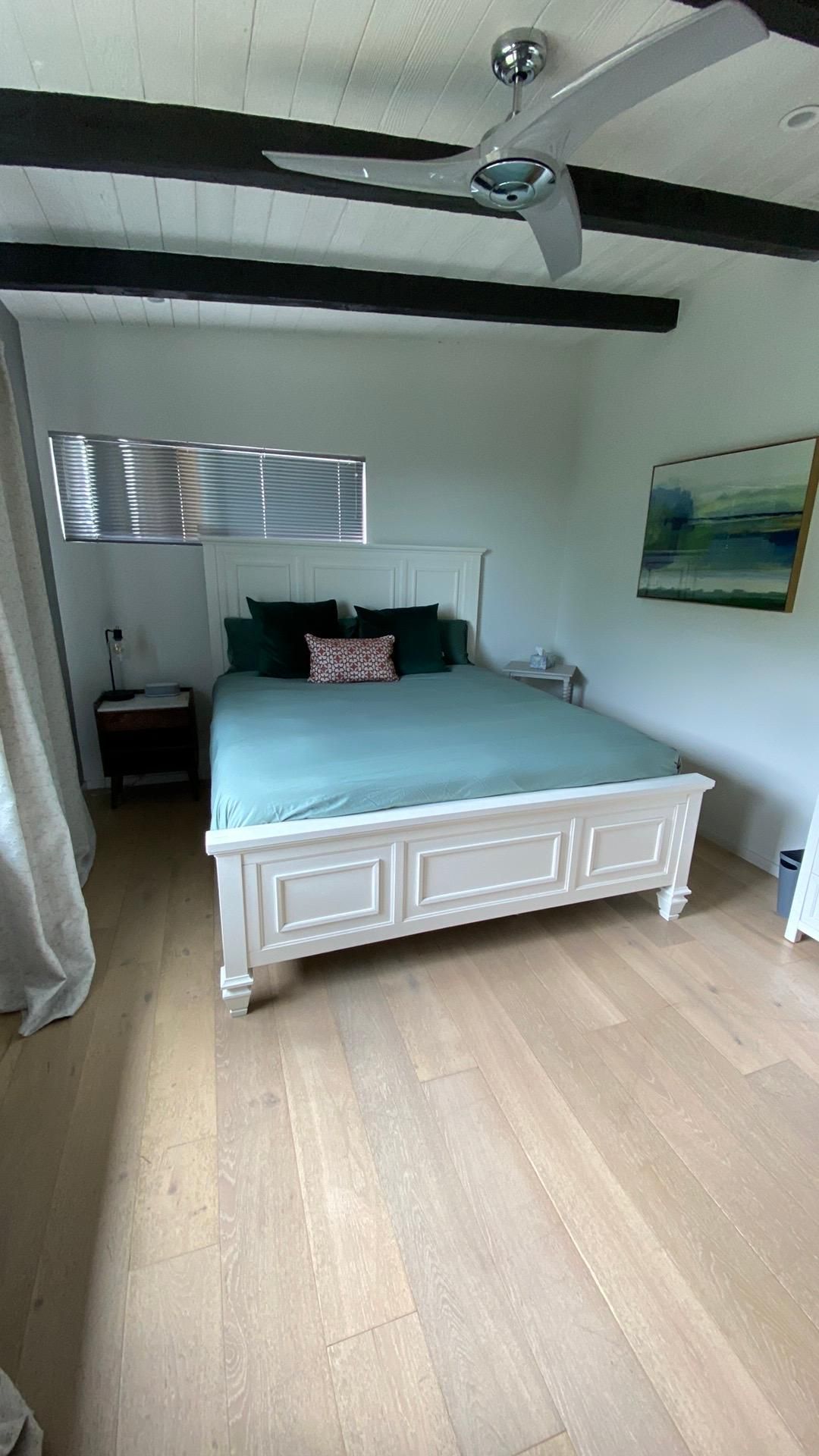 A bedroom with a bed and a ceiling fan.