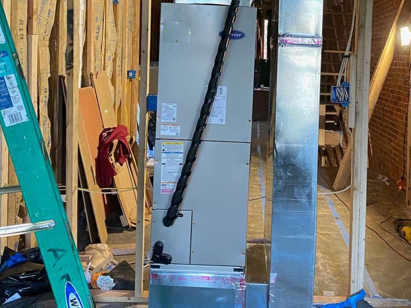 HVAC ductwork installed in an unfinished room with exposed framing and tools.