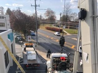 Roadside scene with utility truck, workers, and traffic under overcast sky