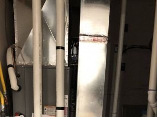 Utility room with white and silver pipes, ducts, and HVAC equipment.