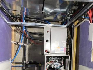 Electrical panel and wiring inside a purple-walled utility cabinet