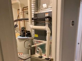 Indoor utility closet with pipes, water heater, and HVAC equipment.