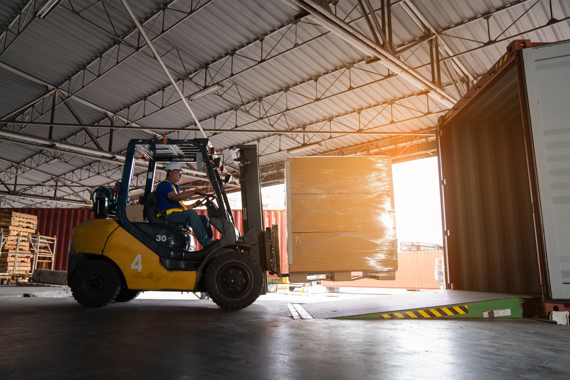 Warehouse worker driver in uniform delivering and loading pallet product by forklift. Warehouse worker driver in uniform delivering and loading pallet product by forklift.