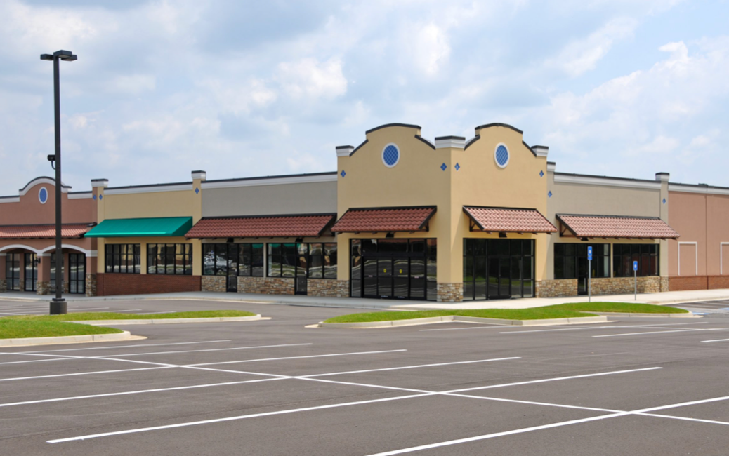 A well-maintained parking lot in front of a commercial building, illustrating the benefits of sweeping services.