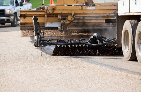 Asphalt paving machine laying fresh asphalt on a road.