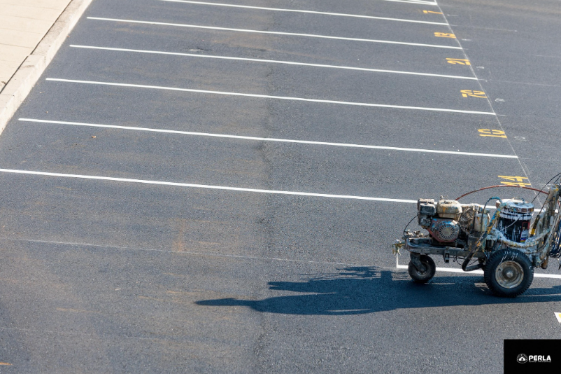 Parking lot striping machine painting white lines. Asphalt surface.