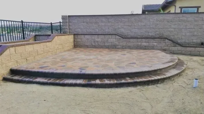 A stone patio with steps, surrounded by retaining walls.