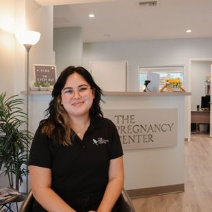 A woman is standing in front of a sign that says the pregnancy center