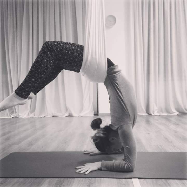 ragazza sospesa che pratica aereal yoga
