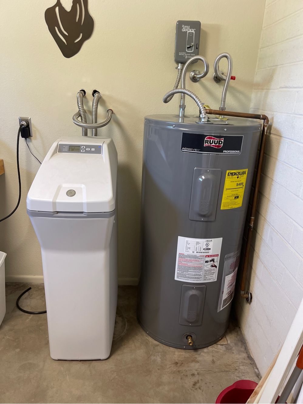 A water softener and a grey water heater stand side-by-side in a utility room.