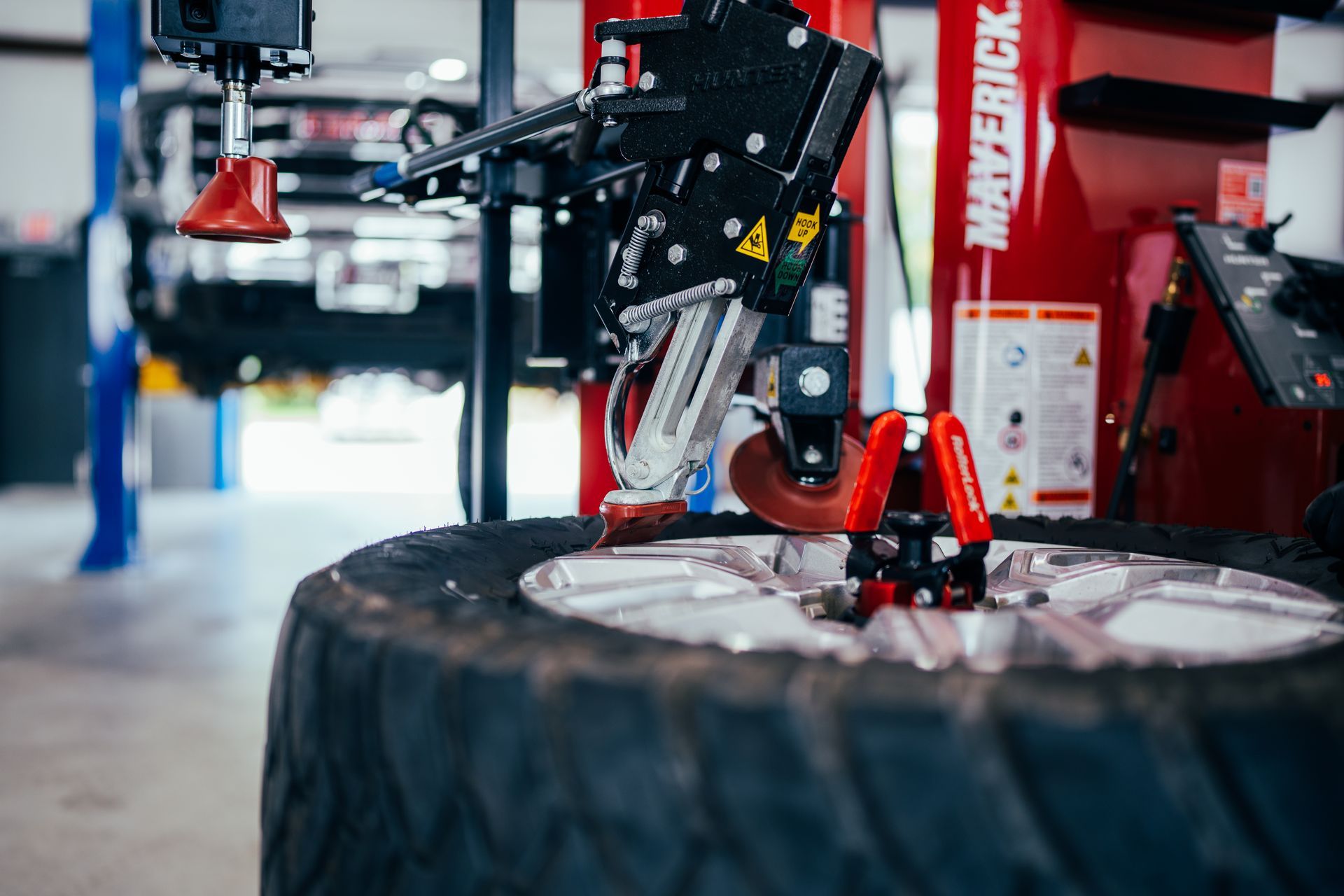 Tire being worked on by a red and black tire machine in a garage setting.