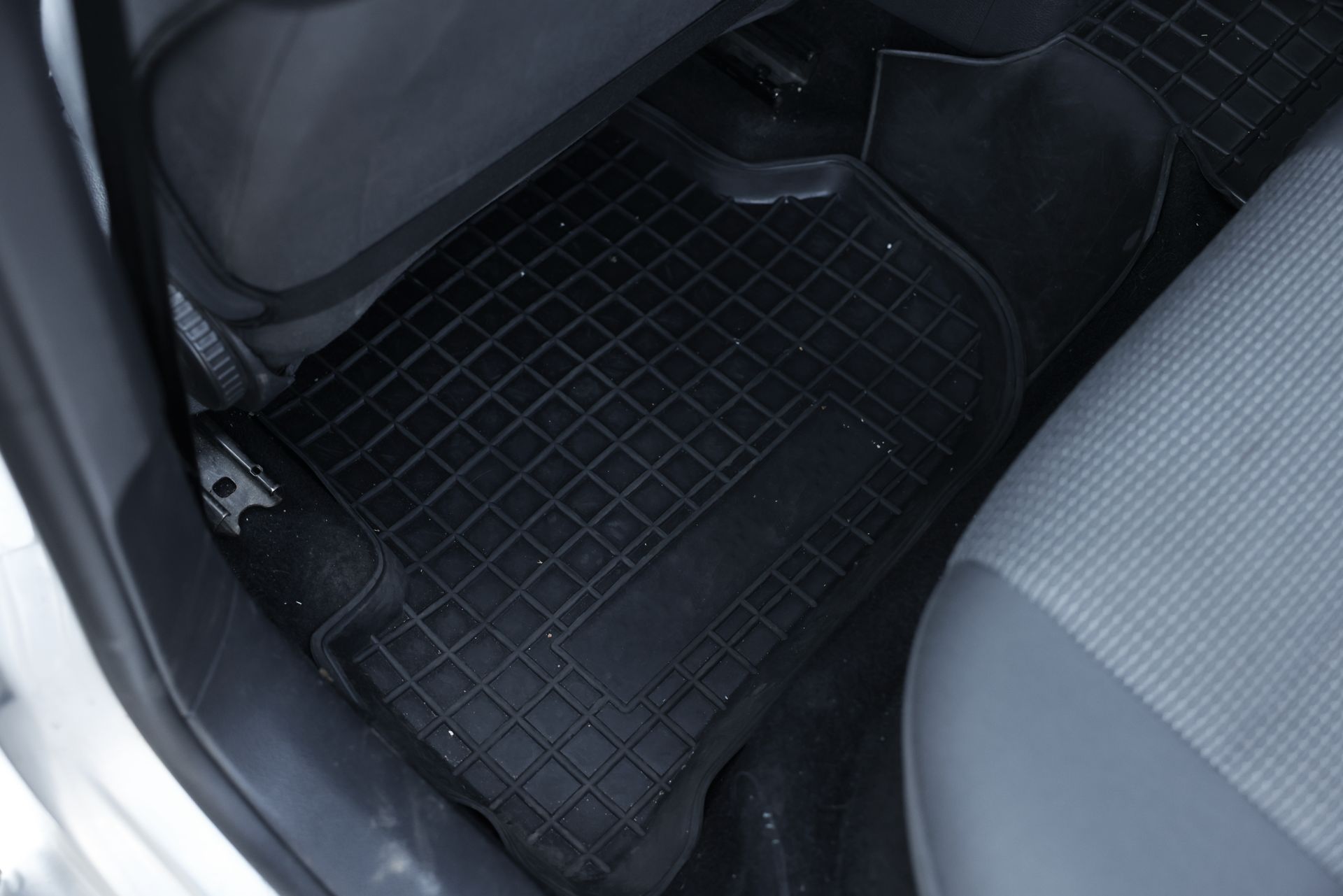 Car interior floor with black rubber mat and gray seat edge