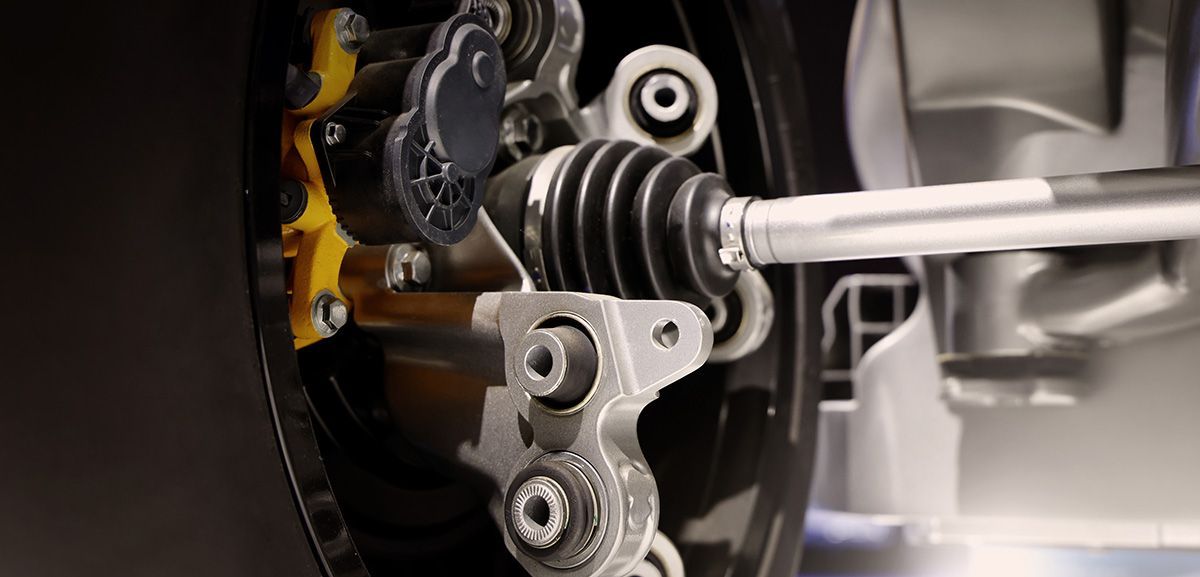 Close-up of a car suspension strut and coil spring assembly with a wrench attached.