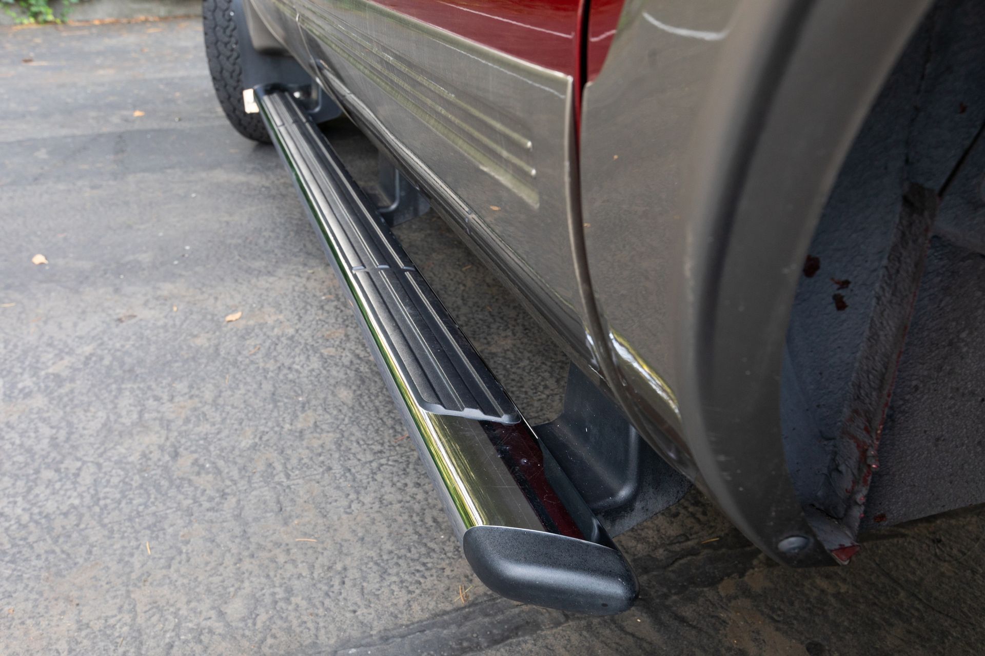 Damaged side step on a maroon SUV, bent away from the vehicle